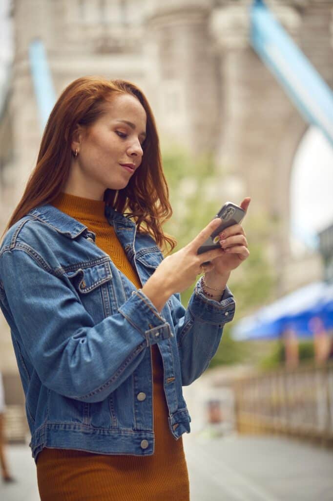 Female Vlogger Or Social Influencer Travelling Through London Using Mobile Phone By Tower Bridge